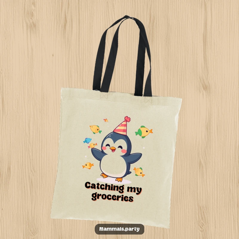 Funny tote bag with a cheerful penguin juggling fish, wearing a party hat, perfect for festive errands and funny gifts.